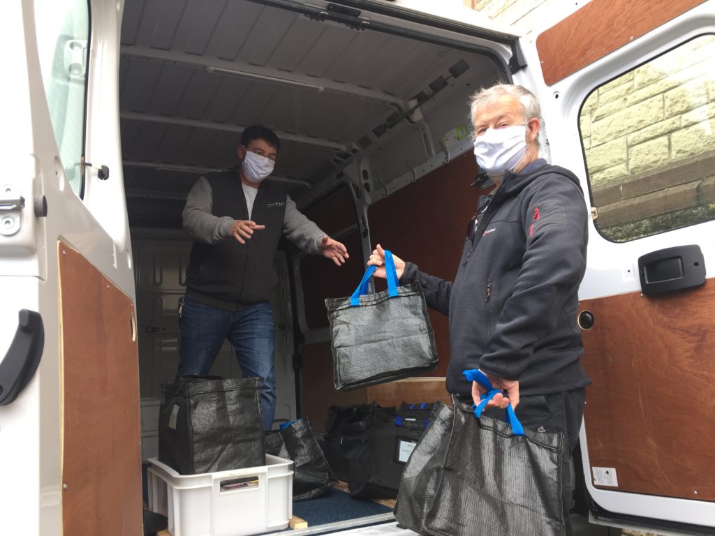 two masked drivers load a library van with home library bags